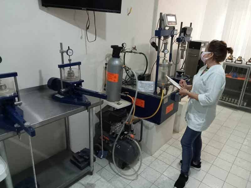 Mujer con bata de laboratorio observando equipos en un laboratorio.
