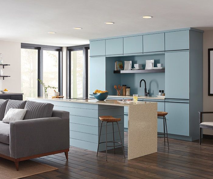 A living room with a couch and a kitchen with blue cabinets