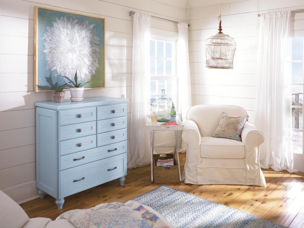 A living room with a blue chest of drawers and a white chair.