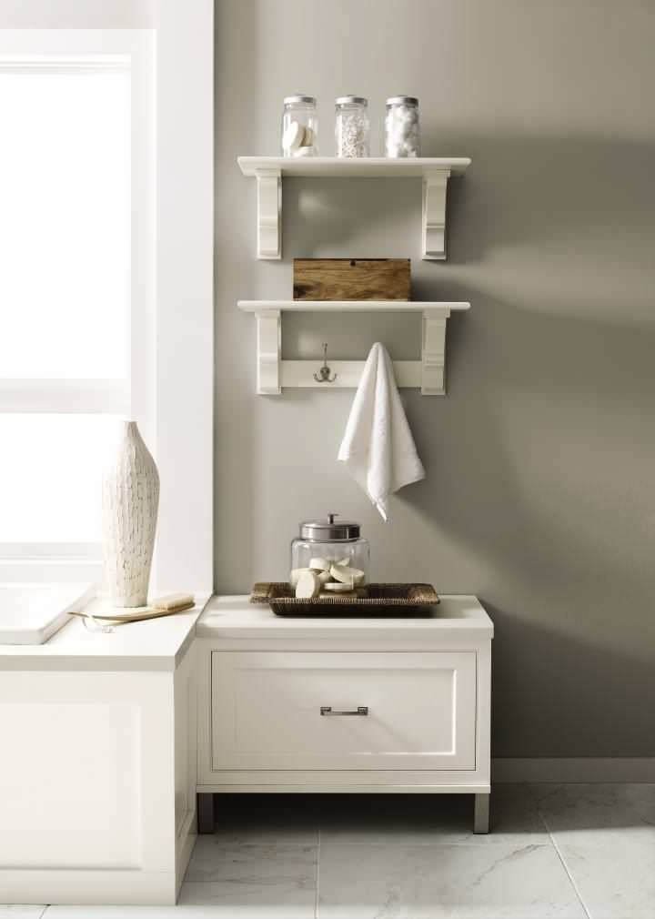 A bathroom with a white cabinet , shelves , and a towel rack.