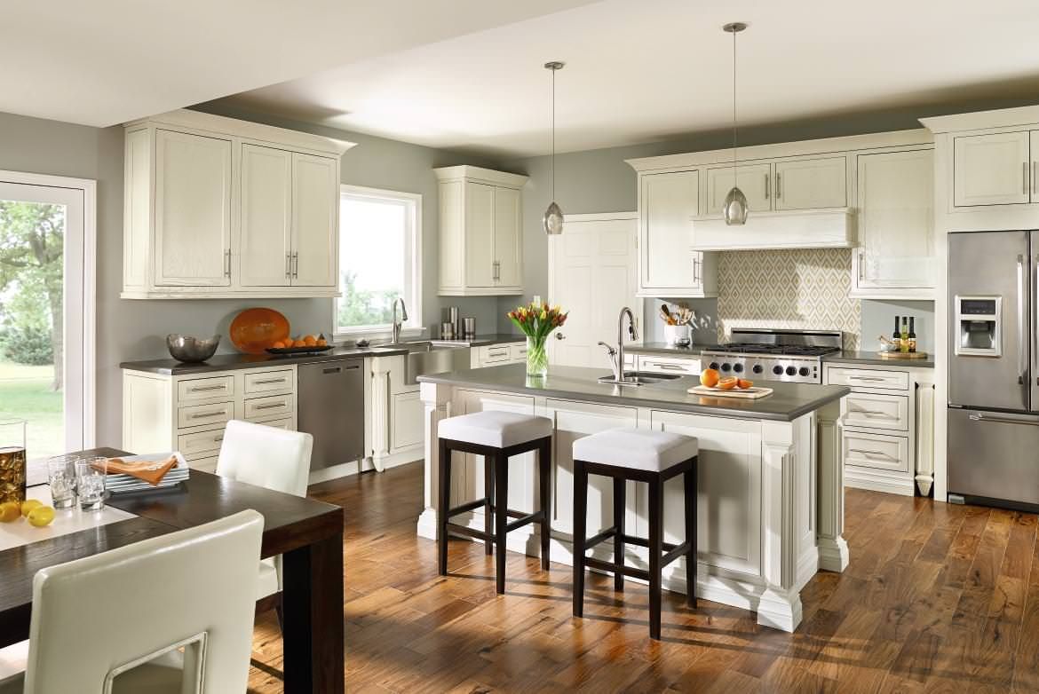 A kitchen with white cabinets , stainless steel appliances , hardwood floors and a large island.