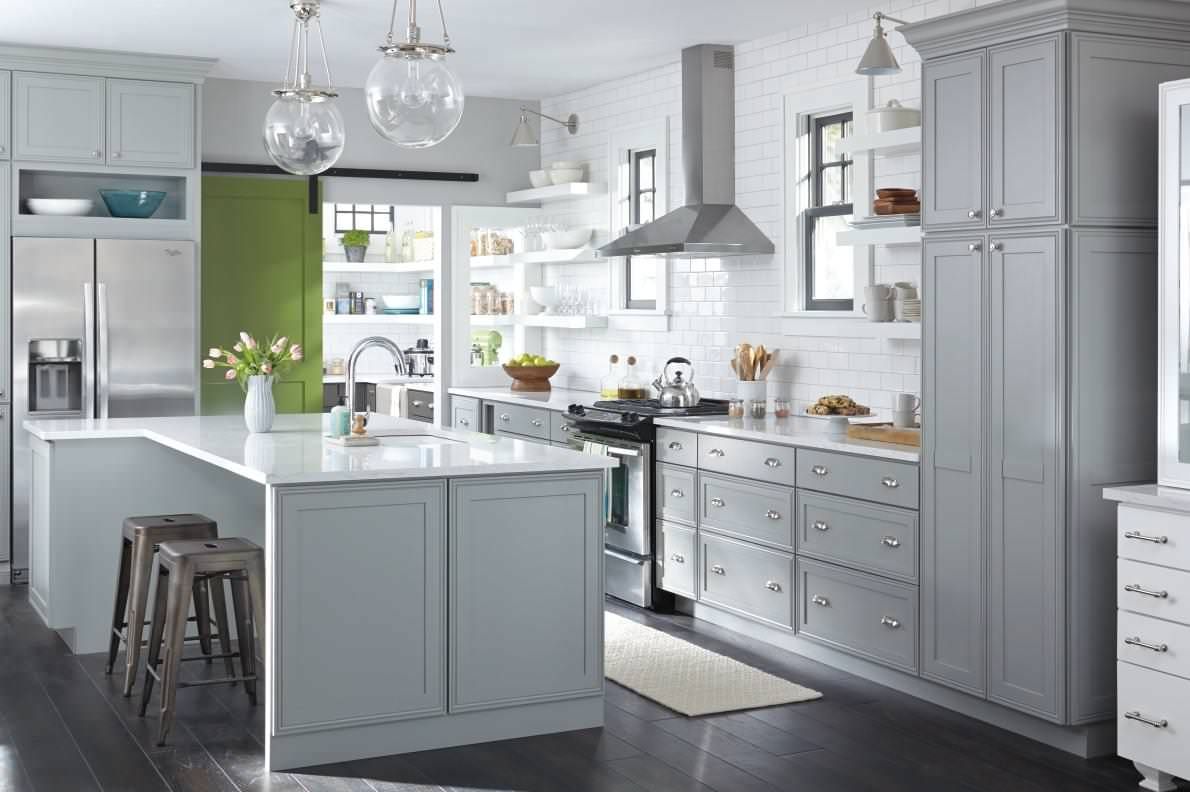 A kitchen with white cabinets , stainless steel appliances , and a large island.