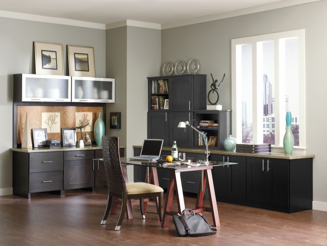 A home office with black cabinets and a desk with a laptop on it
