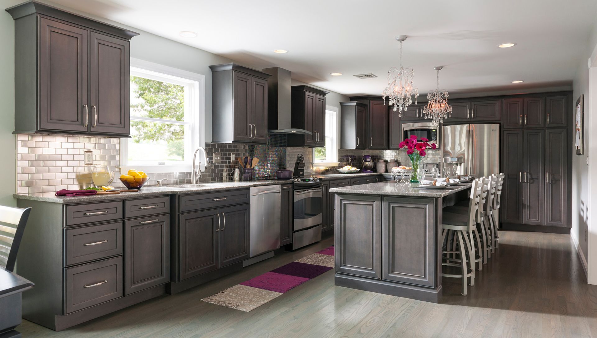 A kitchen with gray cabinets , stainless steel appliances , and a large island.