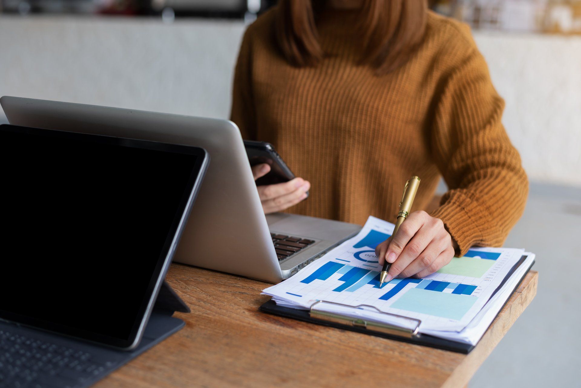 Mujer de negocios sentada frente a la computadora portátil de la tableta con gráficos financieros y estadísticas