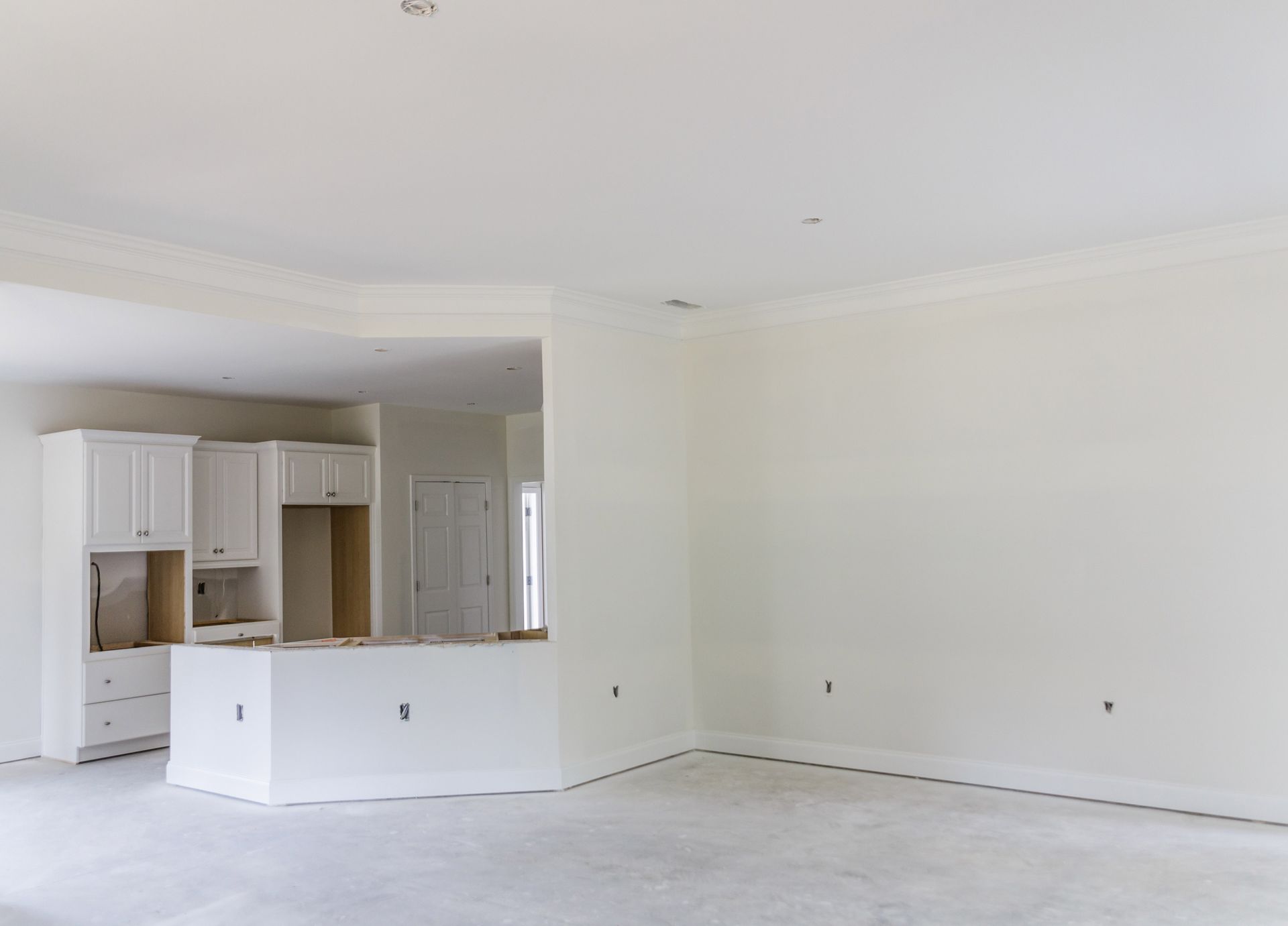 Interior of a room with unfinished kitchen, white walls, and concrete floor. Interior of a room with unfinished kitchen, white walls, and concrete floor.