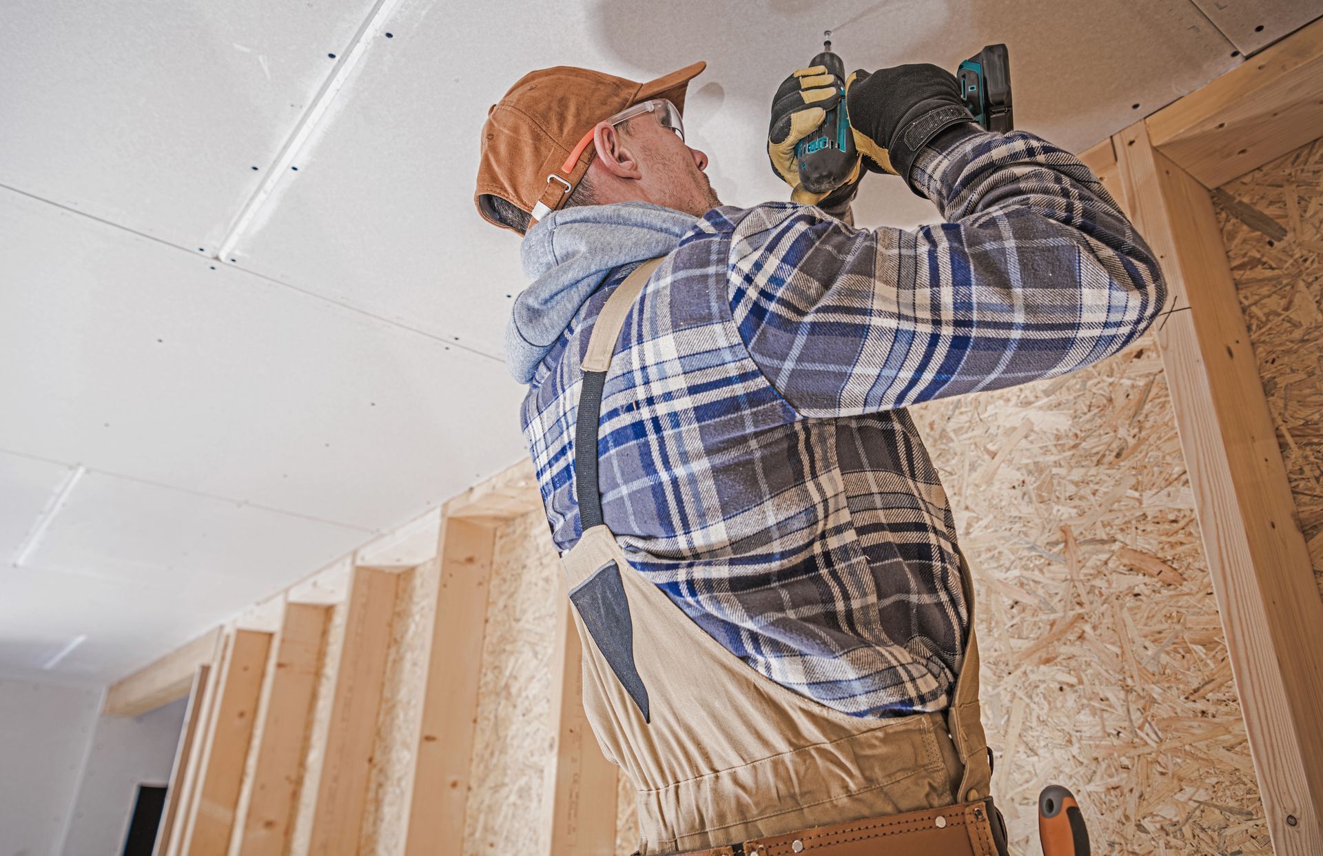 A commercial construction contractor attaching drywall elements to the house ceiling.
