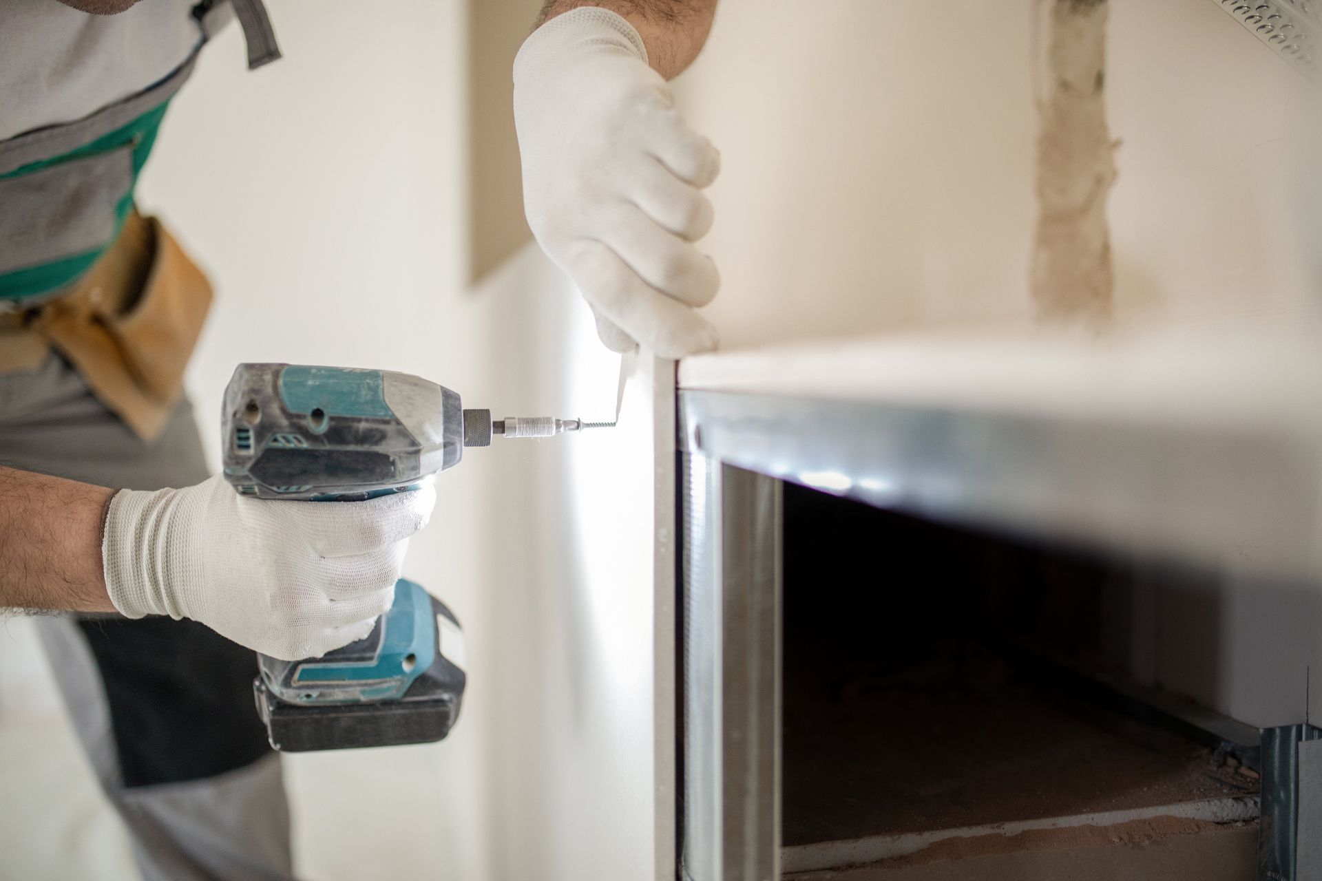 Person in gloves using a power drill to install a counter in a room.