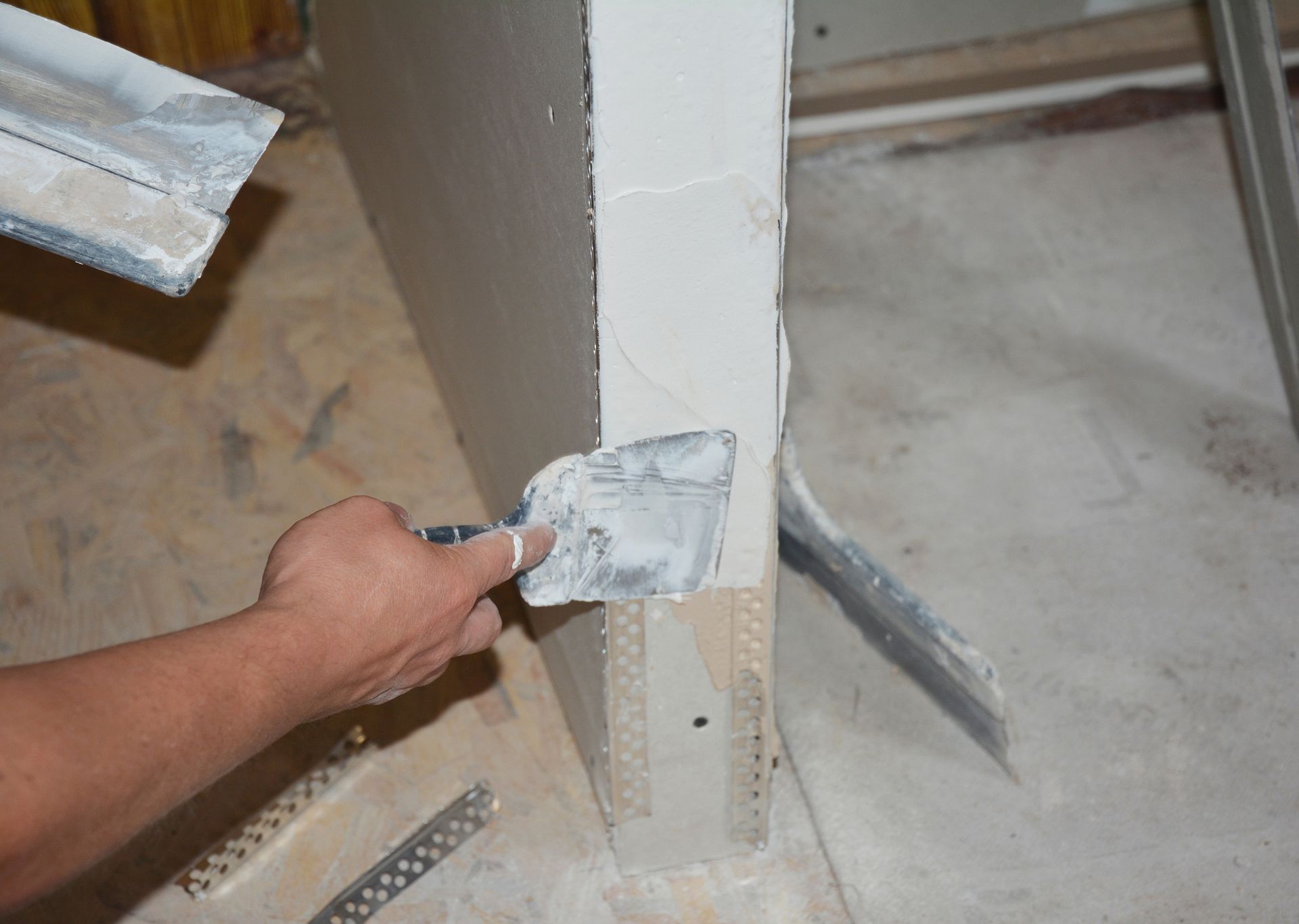 Drywall damage contractor applying a coat of plaster on a drywall partition wall using a spatula. Drywall damage contractor applying a coat of plaster on a drywall partition wall using a spatula.