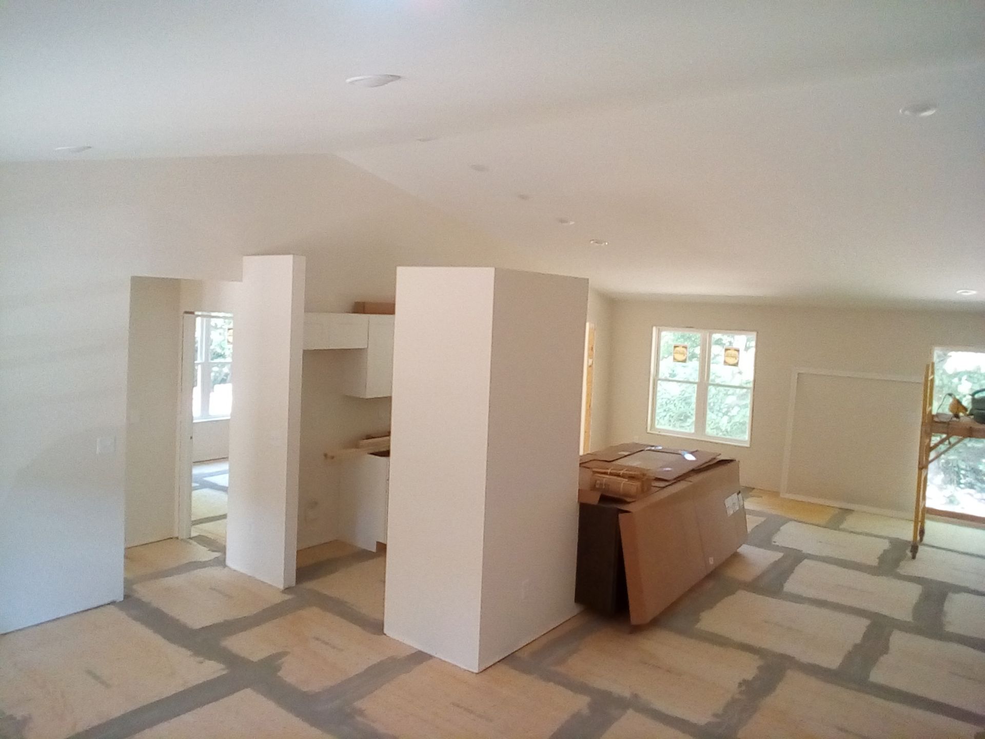 Interior construction of a room with white walls, unfinished flooring, and a central support pillar.