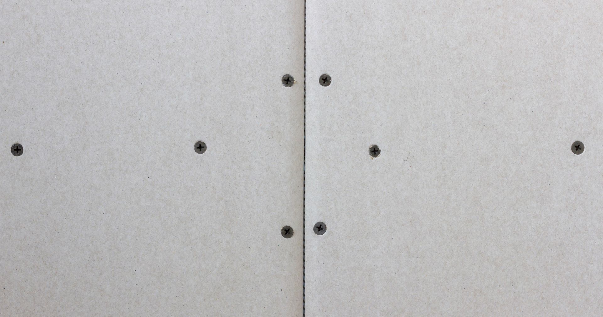 Two drywall panels joined, with visible screws along the edges. Two drywall panels joined, with visible screws along the edges.