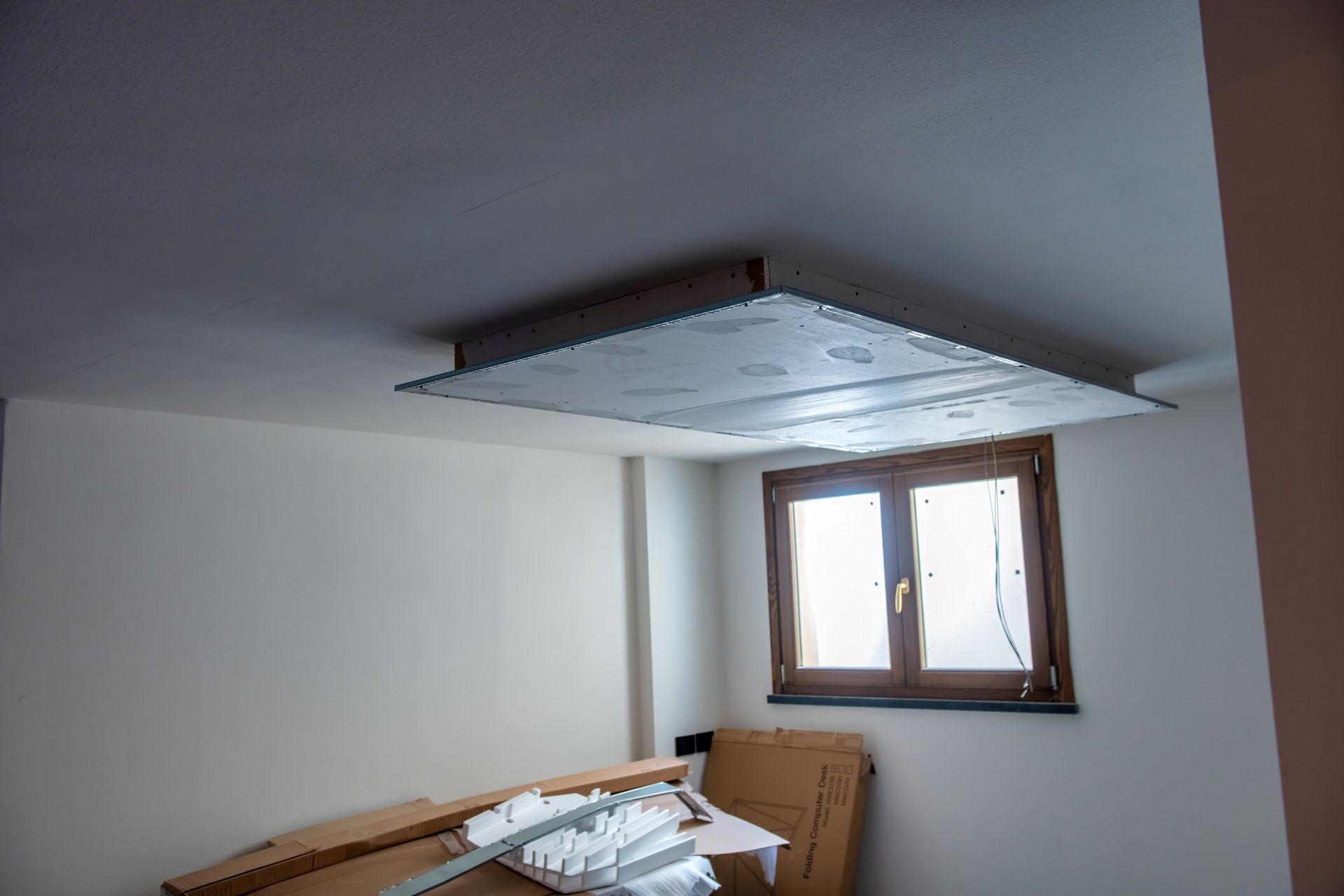 Ceiling insulation panel installation; room with window, boxes, and drywall. Ceiling insulation panel installation; room with window, boxes, and drywall.