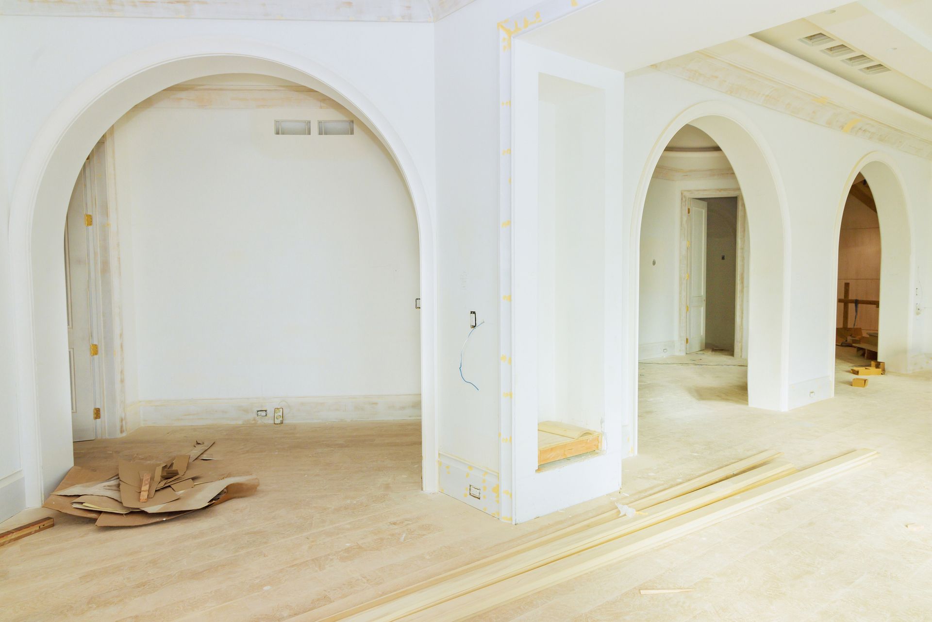 Interior with white arches and doorways; unfinished construction with debris on floor.