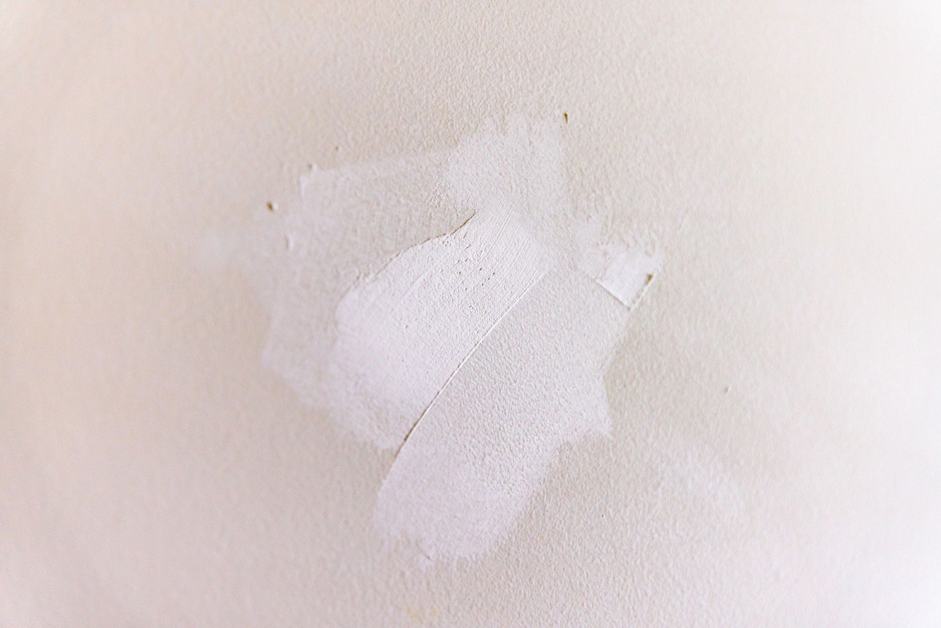 White wall with a patch of white repair compound. White wall with a patch of white repair compound.