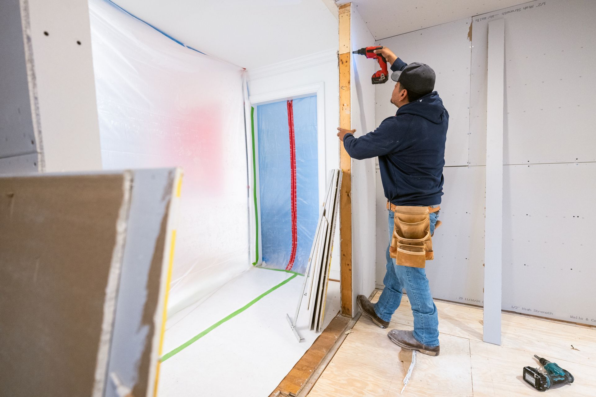 Skilled contractor installing new drywall in a residential kitchen. Skilled contractor installing new drywall in a residential kitchen.