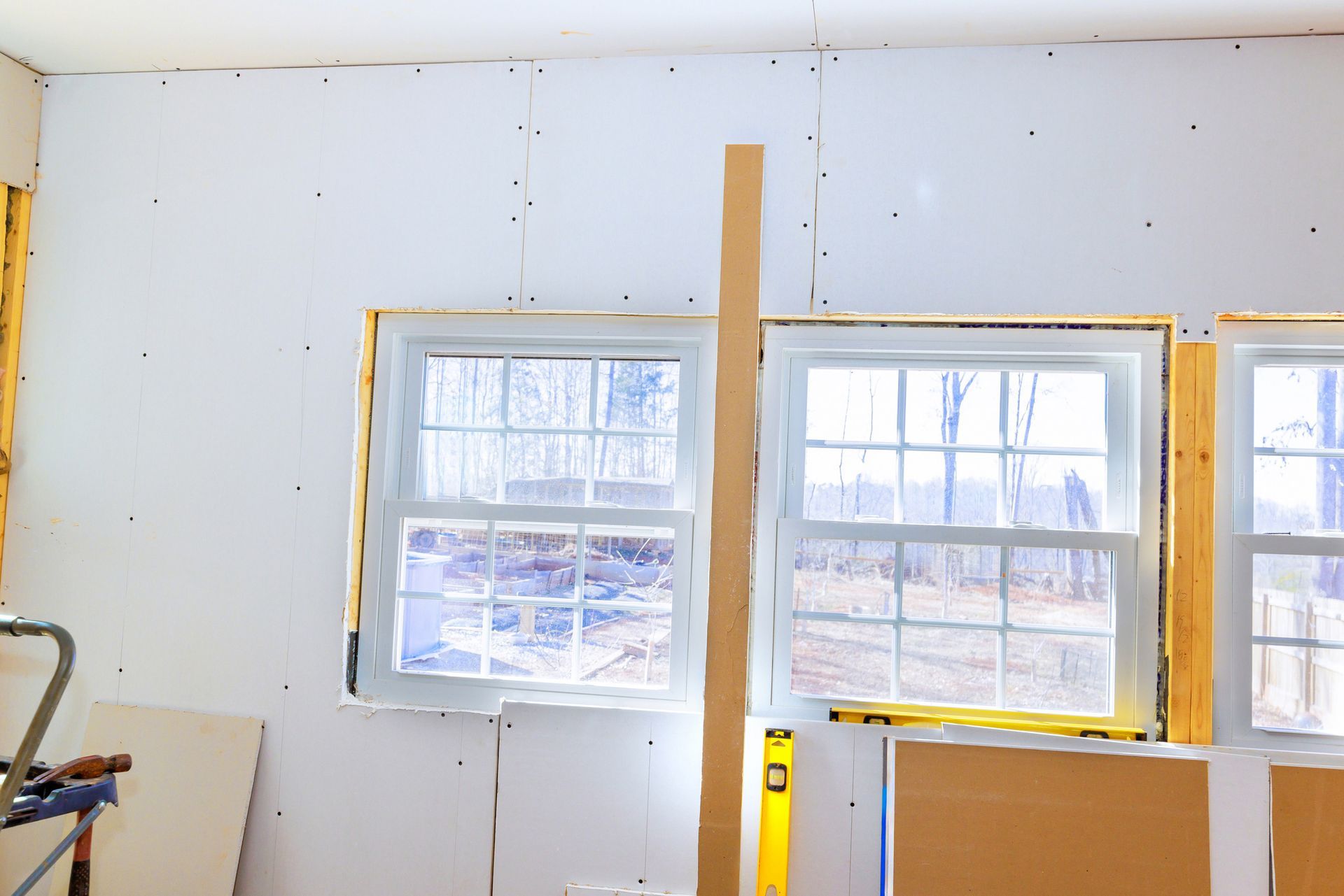 Room renovation with drywall around windows, wood studs, and a level. Room renovation with drywall around windows, wood studs, and a level.