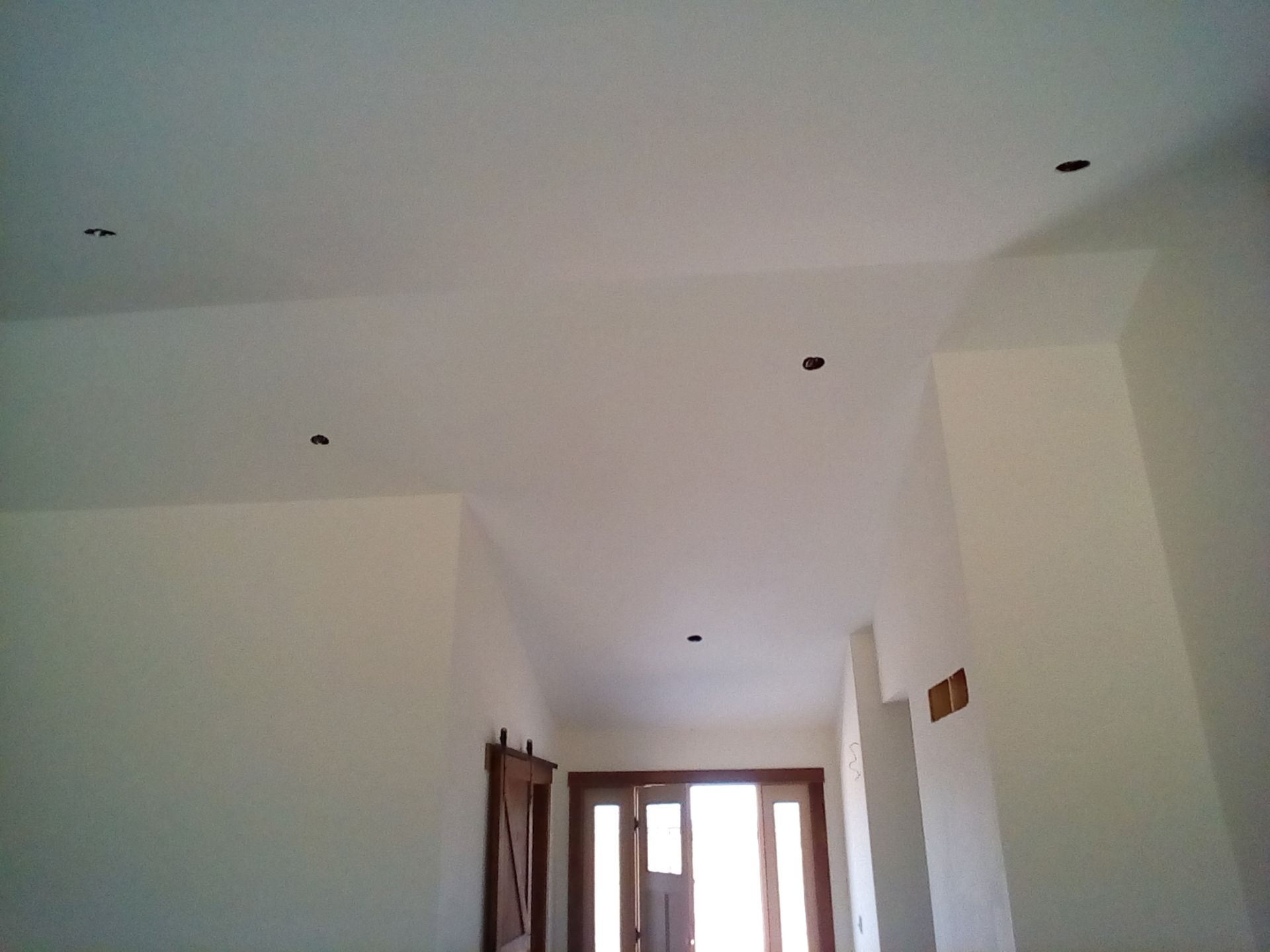 An interior view of a cream-colored room, doorway, and ceiling with recessed lighting. An interior view of a cream-colored room, doorway, and ceiling with recessed lighting.