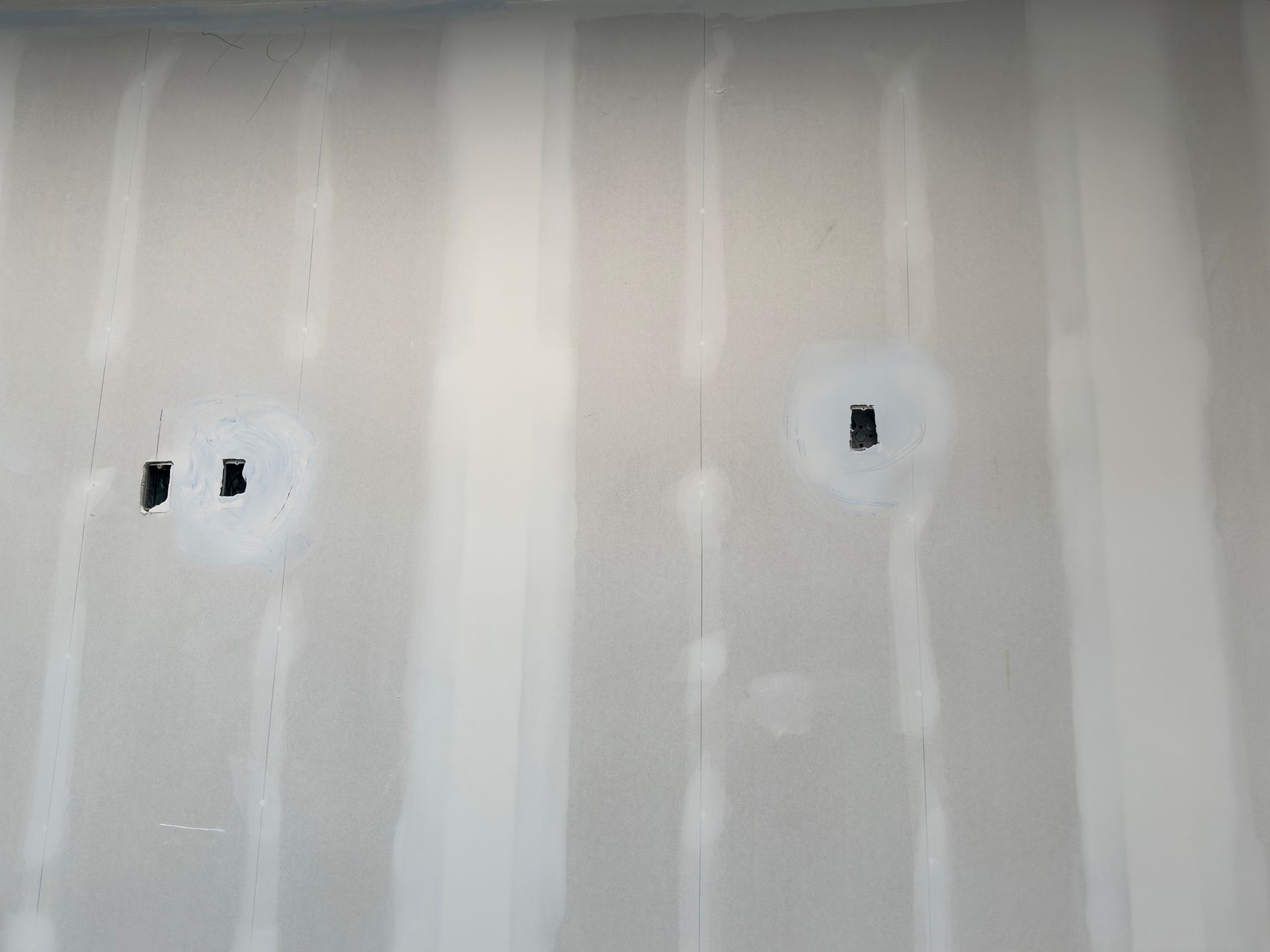 Drywall with two patched holes for electrical outlets.