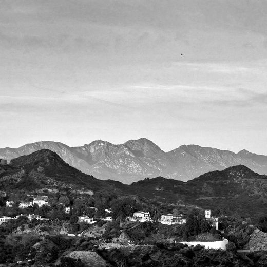 A black and white photo of a valley with mountains in the background