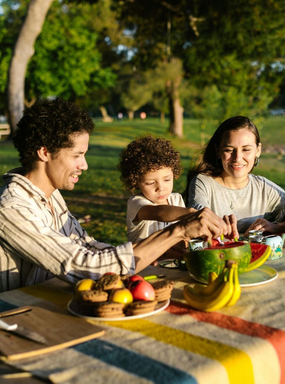 A family is having a picnic in the park and eating fruit.