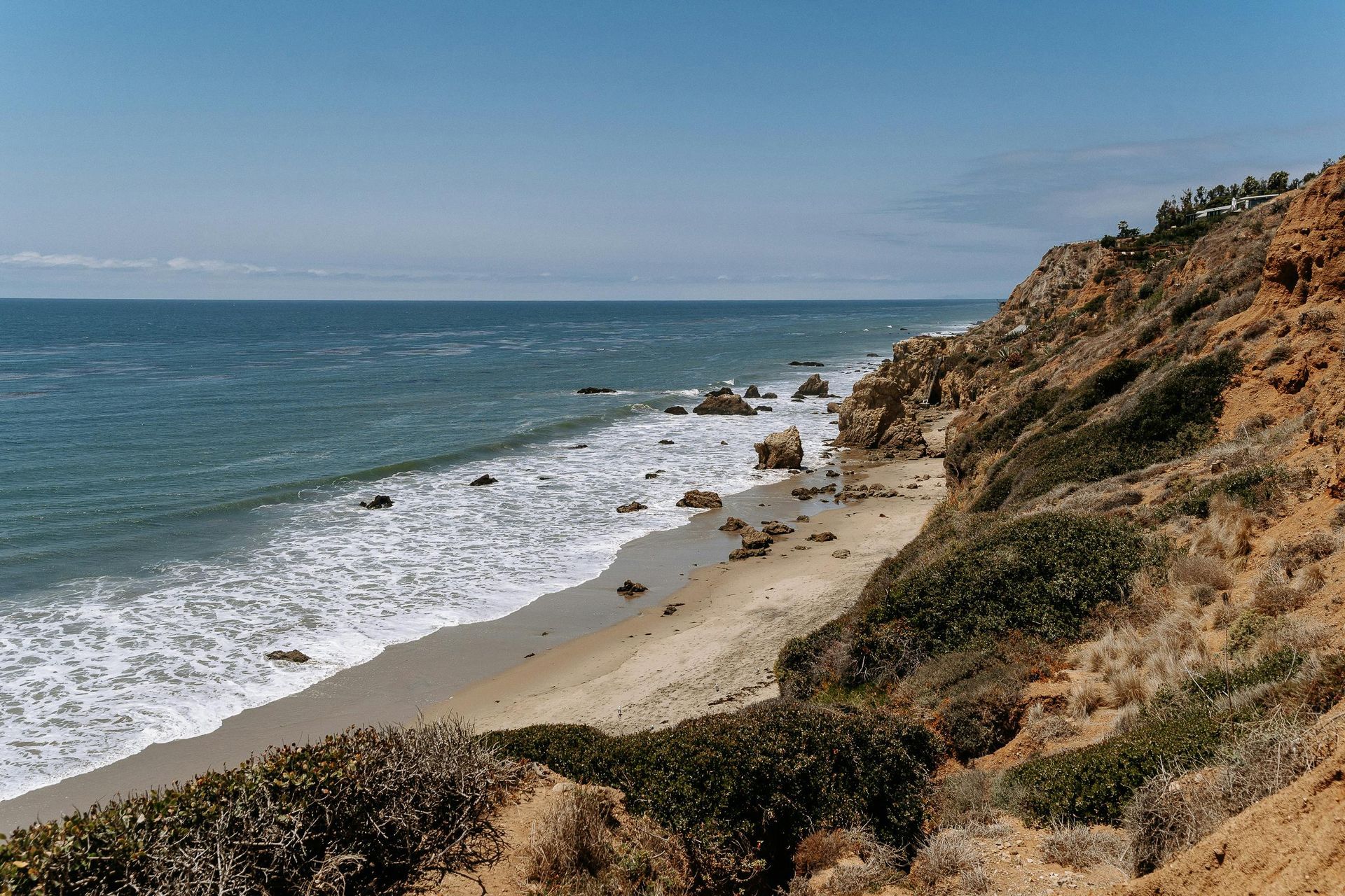 A beach with waves crashing against a rocky cliff