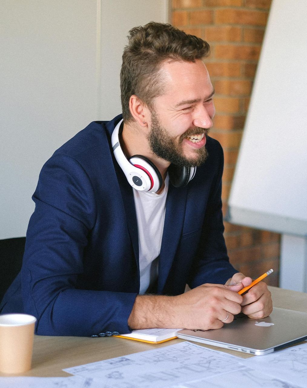 A man wearing headphones is sitting at a table with a laptop.