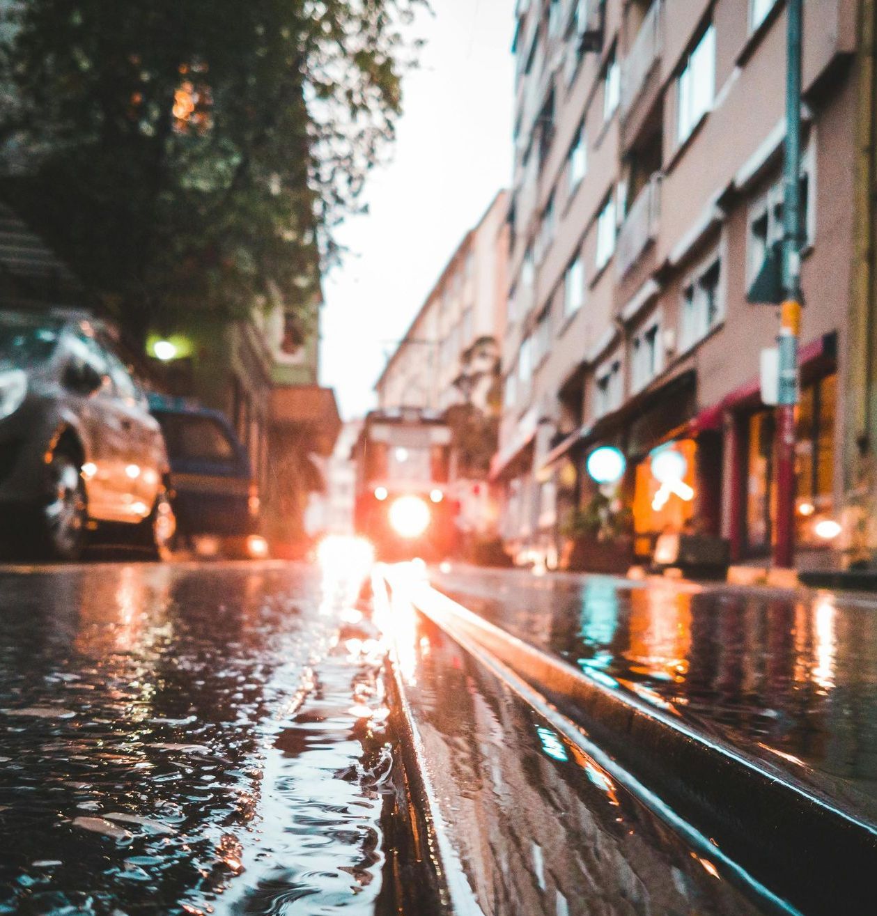 A car is driving down a wet city street in the rain.