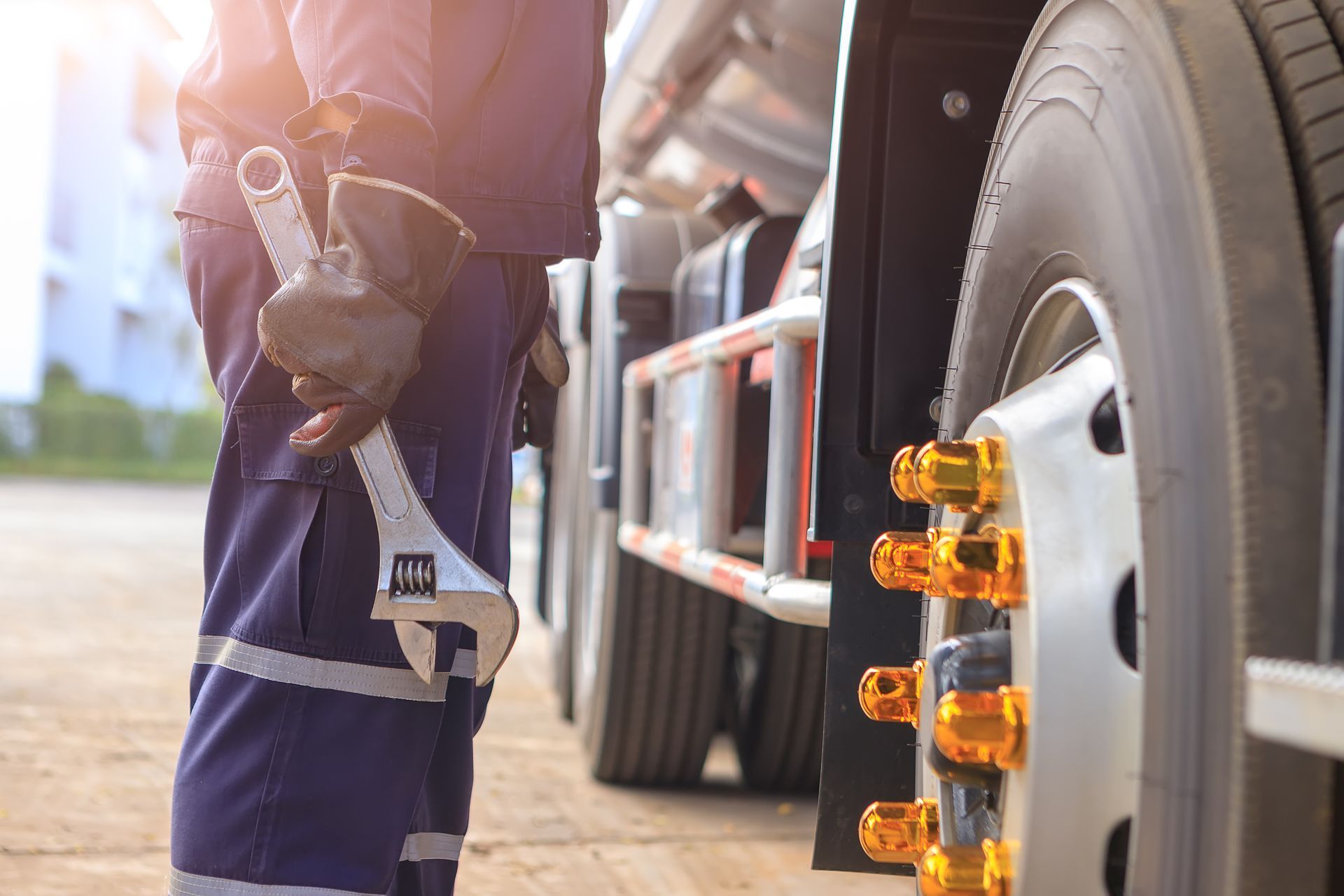 Semi-truck repair technician inspecting a truck wheel with a wrench