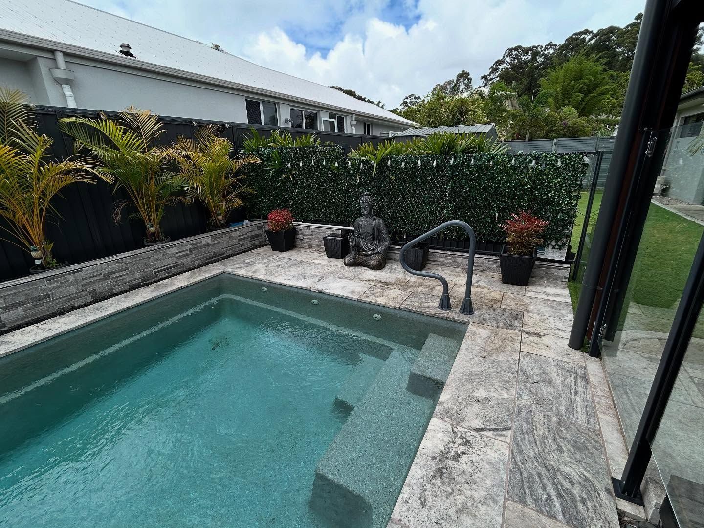 Small Plunge Pool With A Buddha Statue And Potted Plants On The Deck