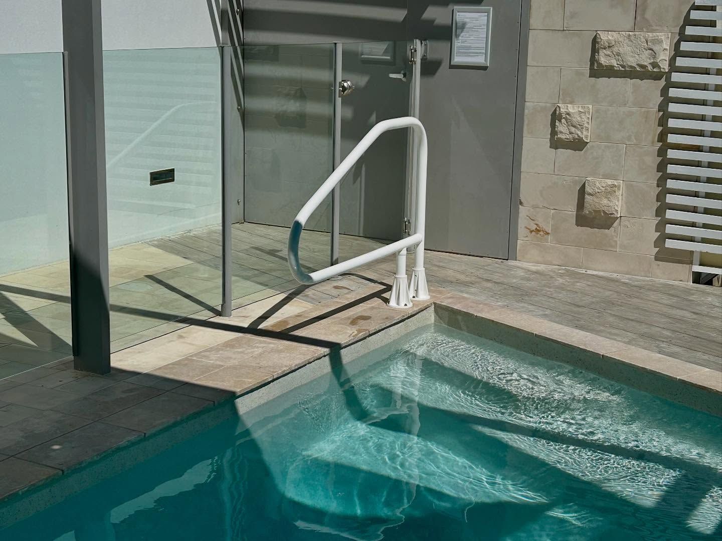White Handrail And Glass Fence On A Residential Pool Deck