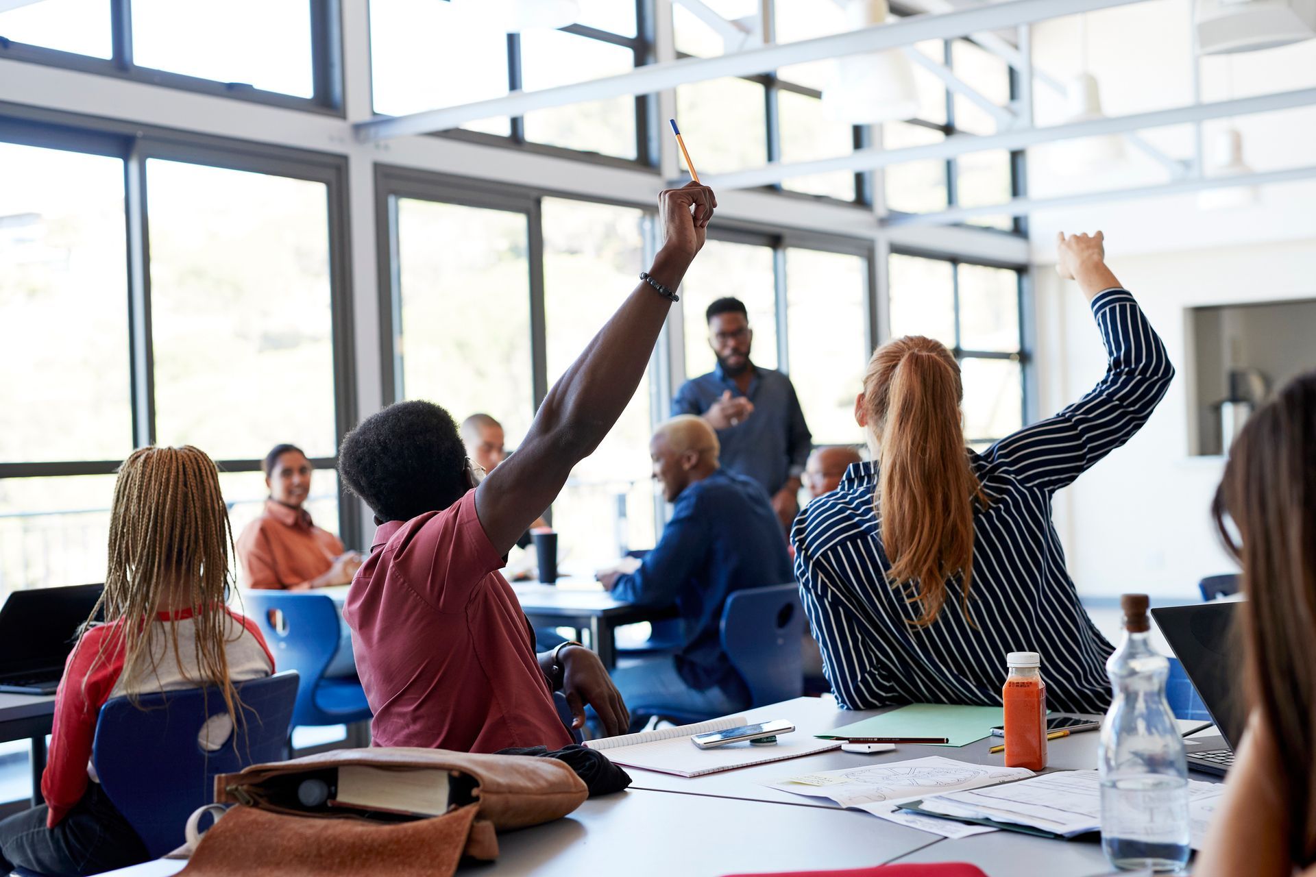 A group of students are raising their hands in a classroom.
