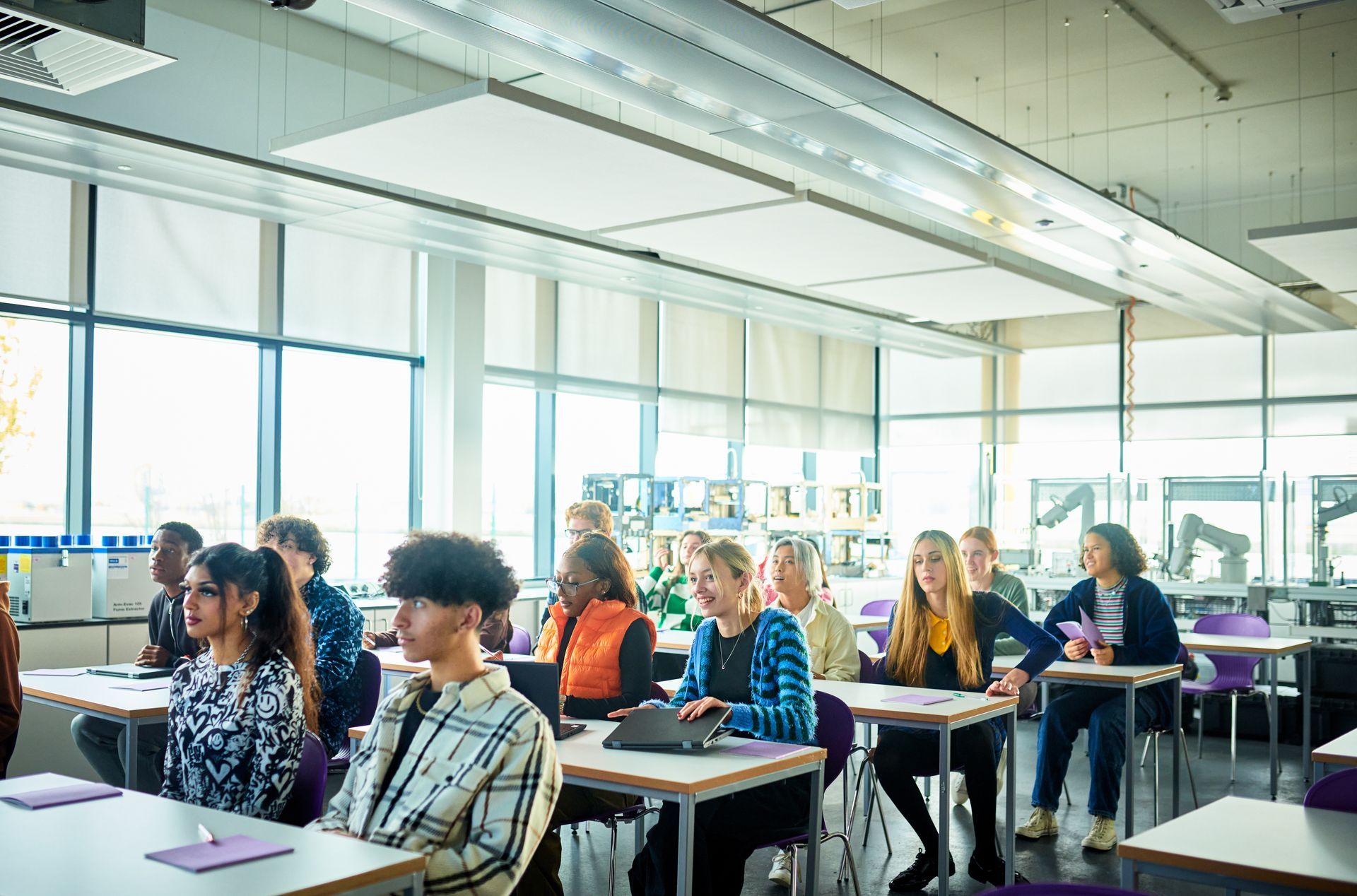 A group of people are sitting at tables in a classroom.