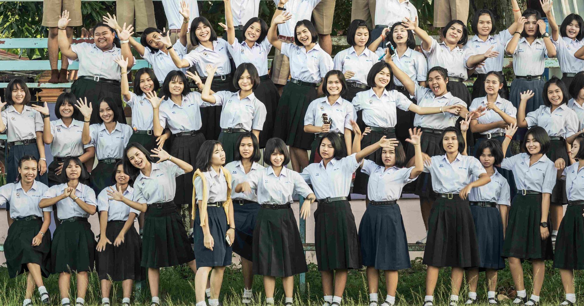 A large group of people in school uniforms are posing for a picture.