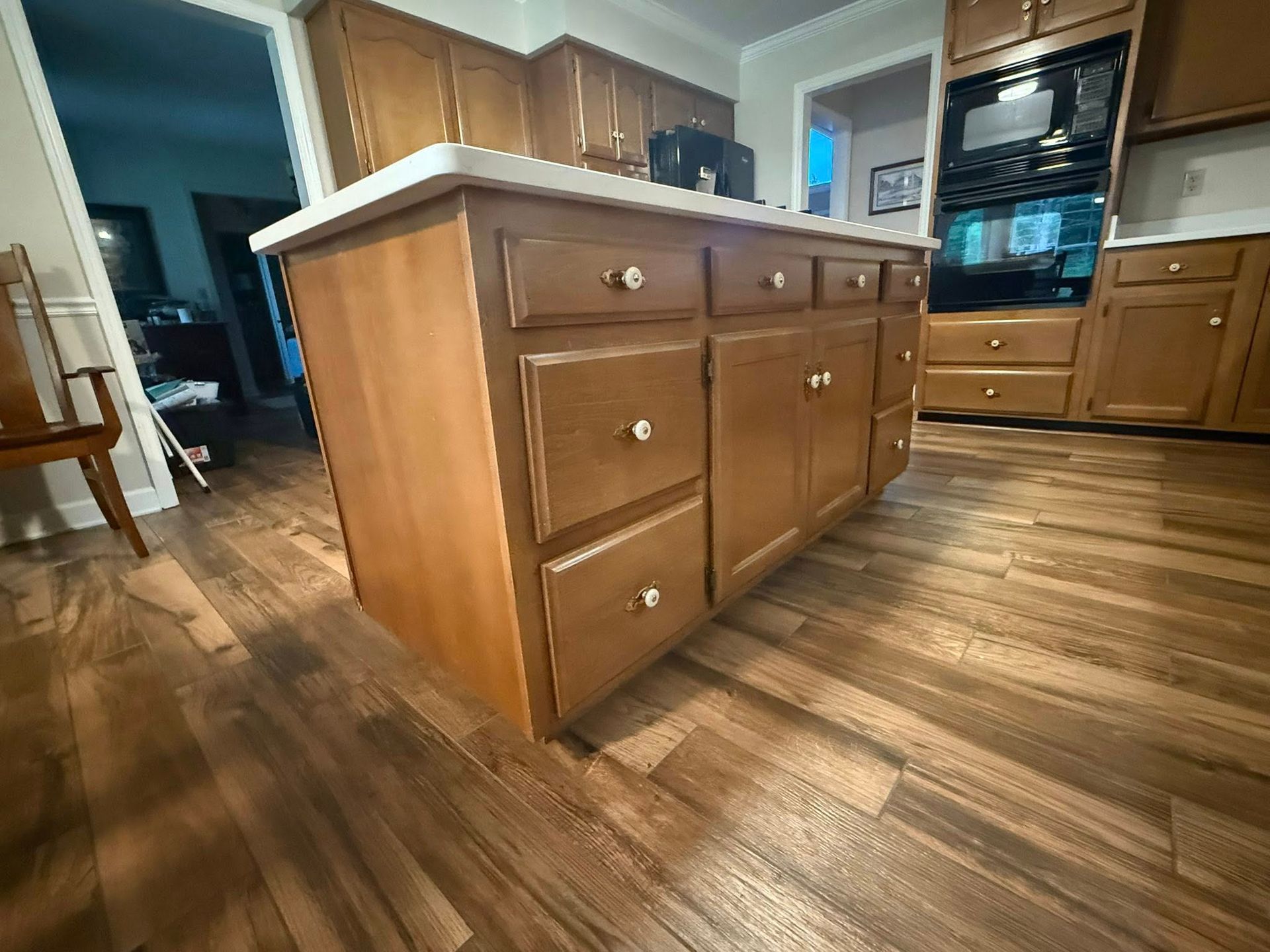 Kitchen island with wood cabinets, white countertop, and wood floor.