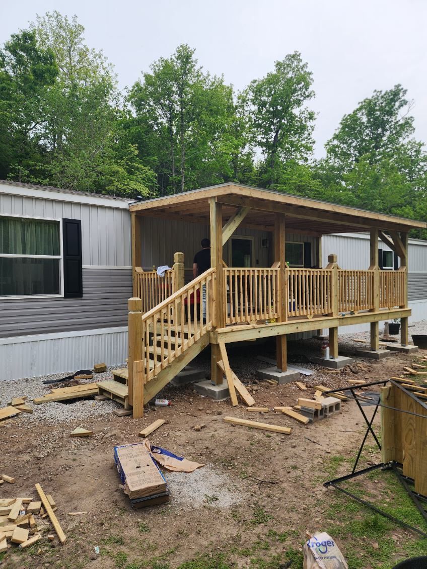 Wooden porch and stairs attached to a mobile home, under construction outdoors.