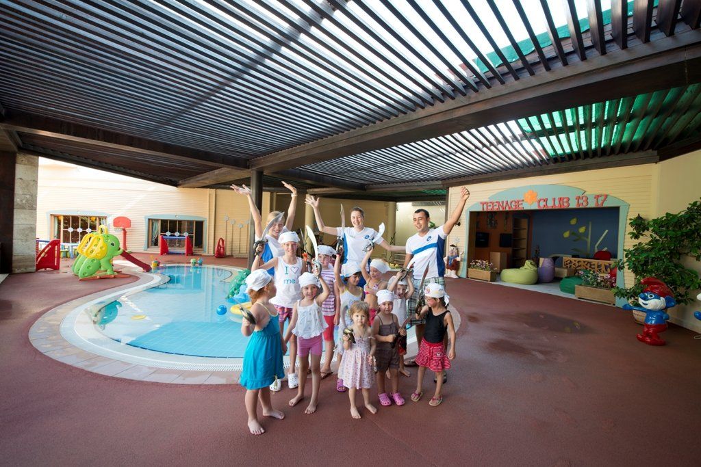 A group of children are posing for a picture in front of a swimming pool.