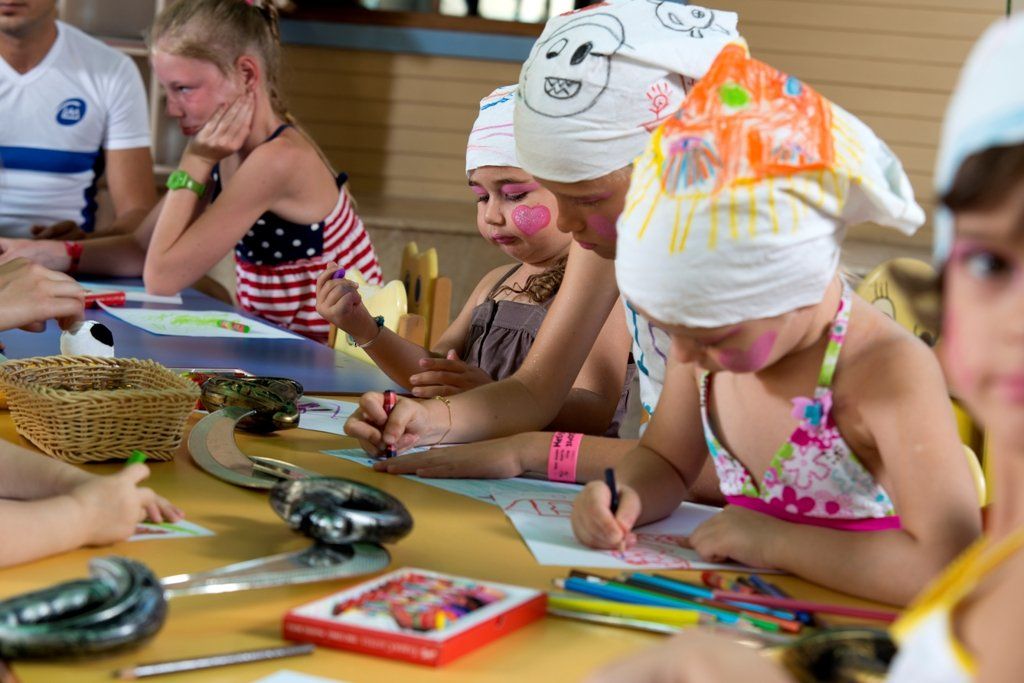 A group of children are sitting at a table drawing.
