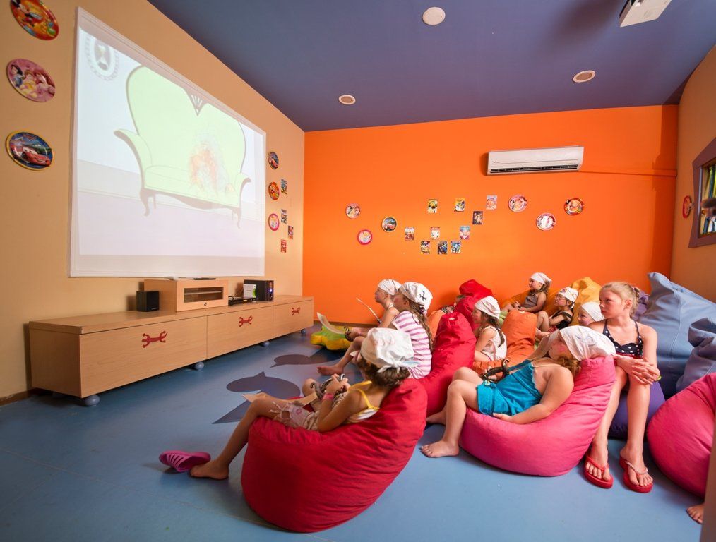 Группа детей сидит в креслах-мешках перед экраном проектора.