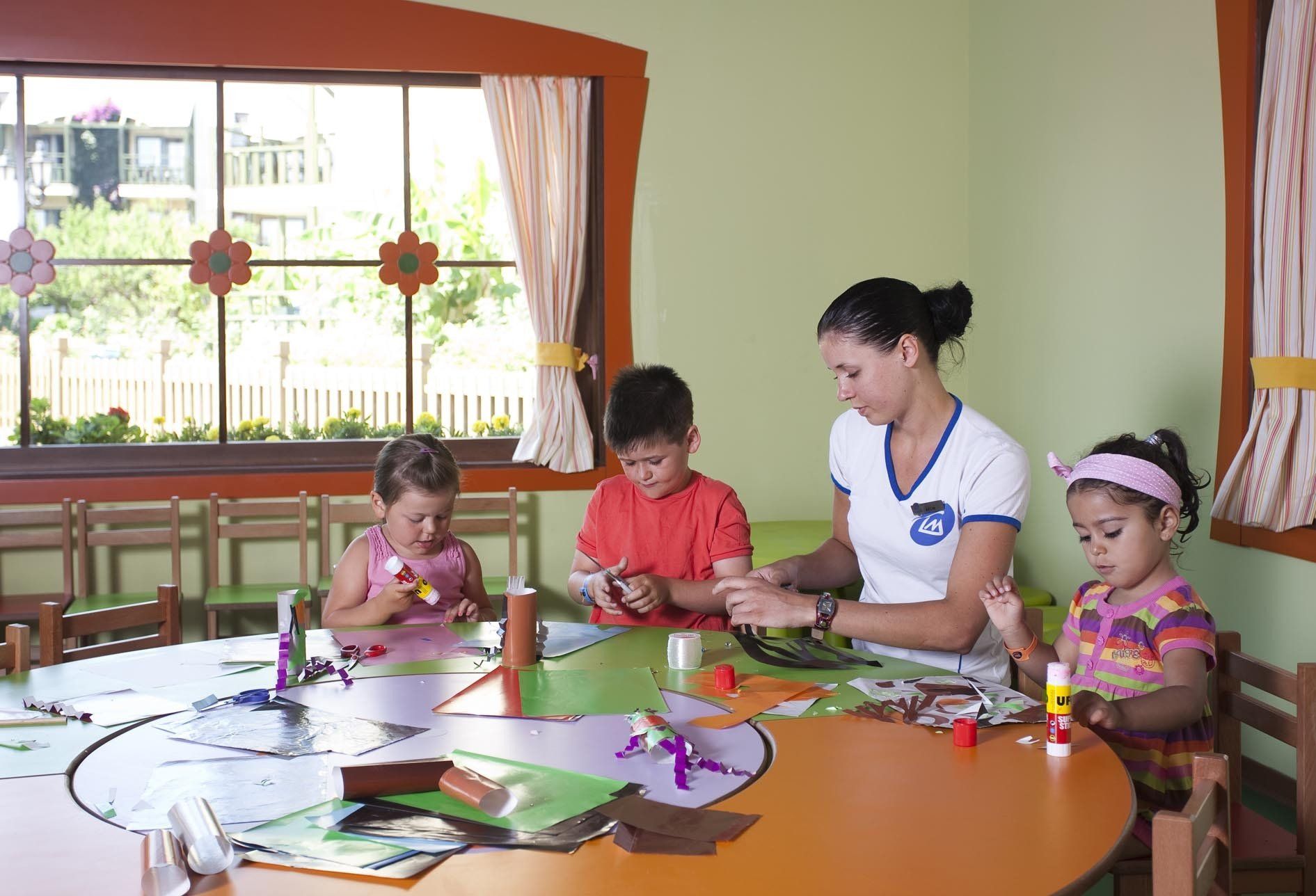 Eine Frau sitzt mit drei Kindern an einem Tisch.
