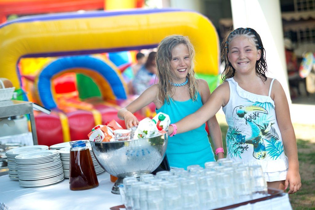 Two young girls are standing next to each other at a buffet table.