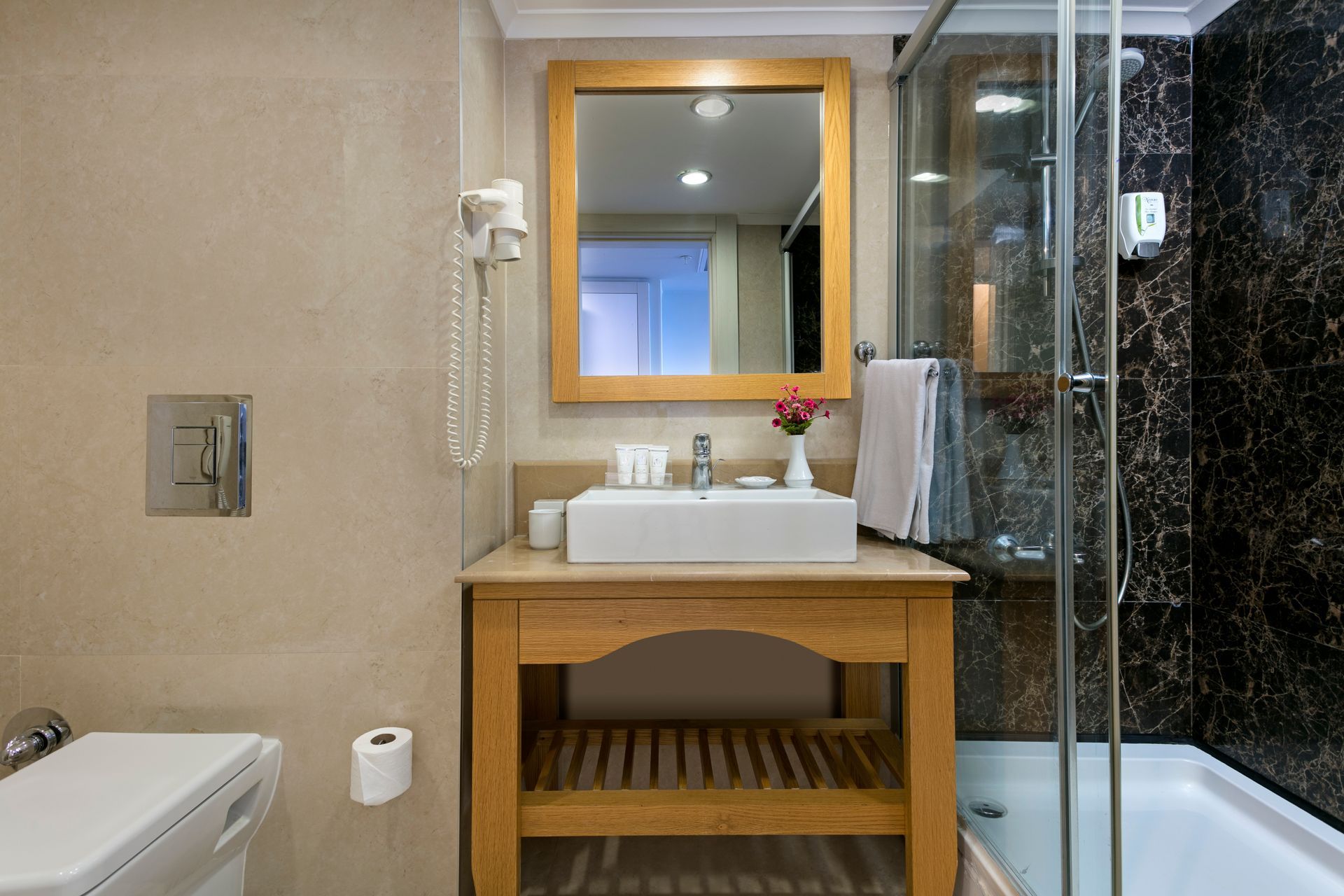 A bathroom with a sink , toilet , shower and mirror.