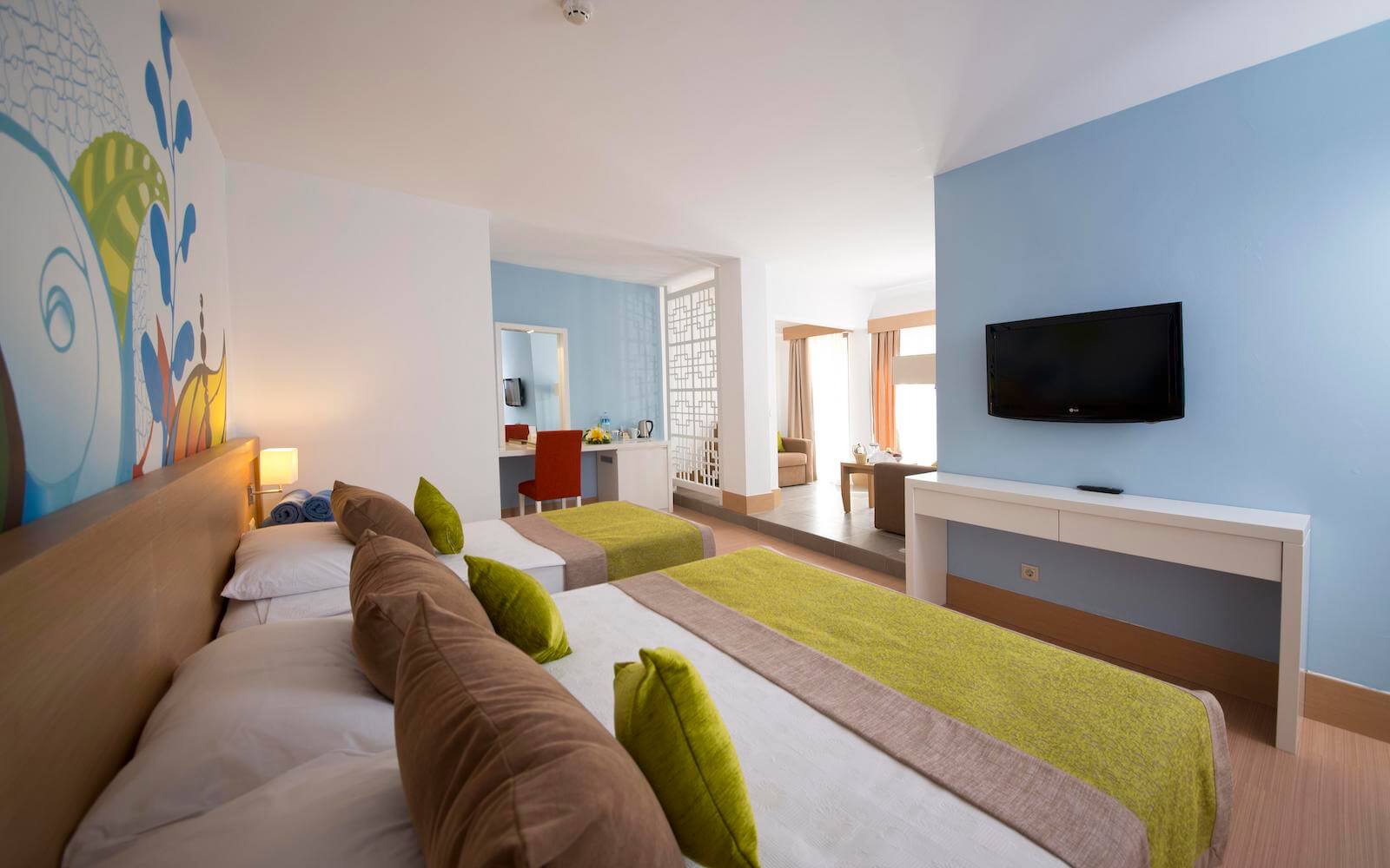 Ein Hotelzimmer mit zwei Betten und einem Flachbildfernseher an der Wand.