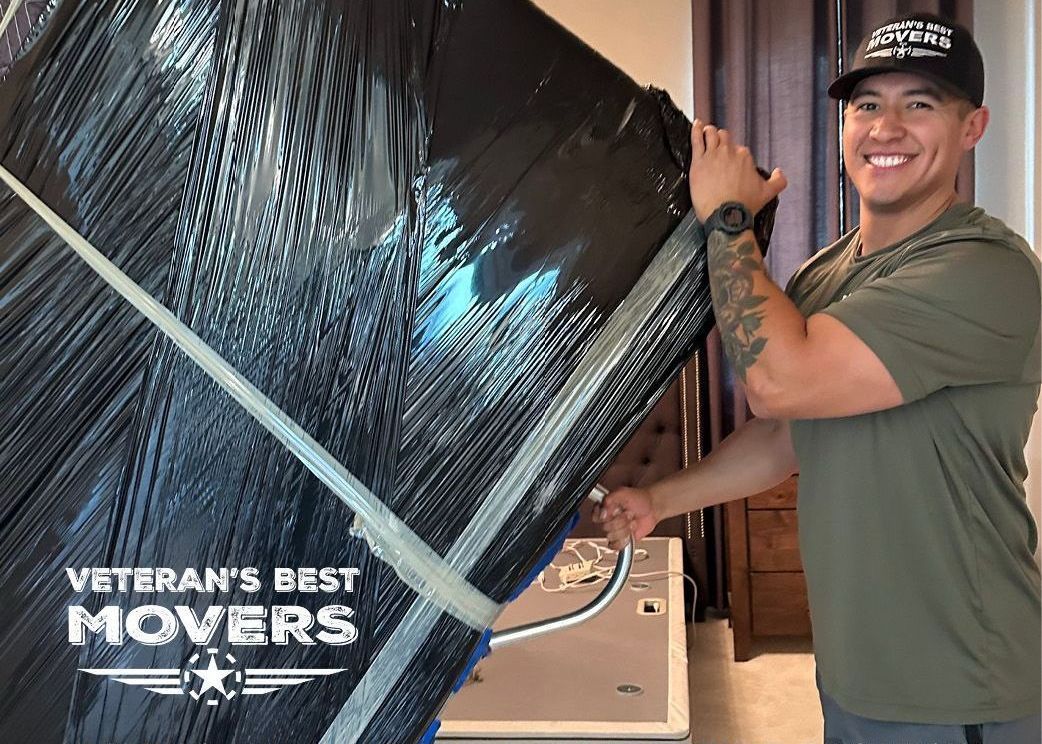 A man is wrapping a large piece of furniture in plastic wrap.