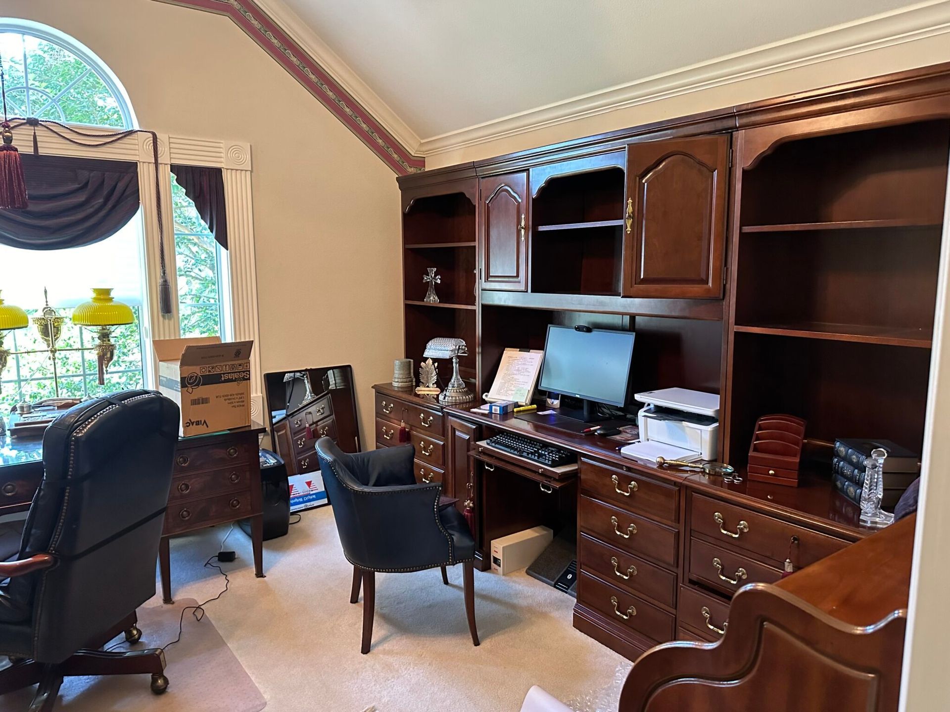A home office with a desk , chairs , shelves and a computer.