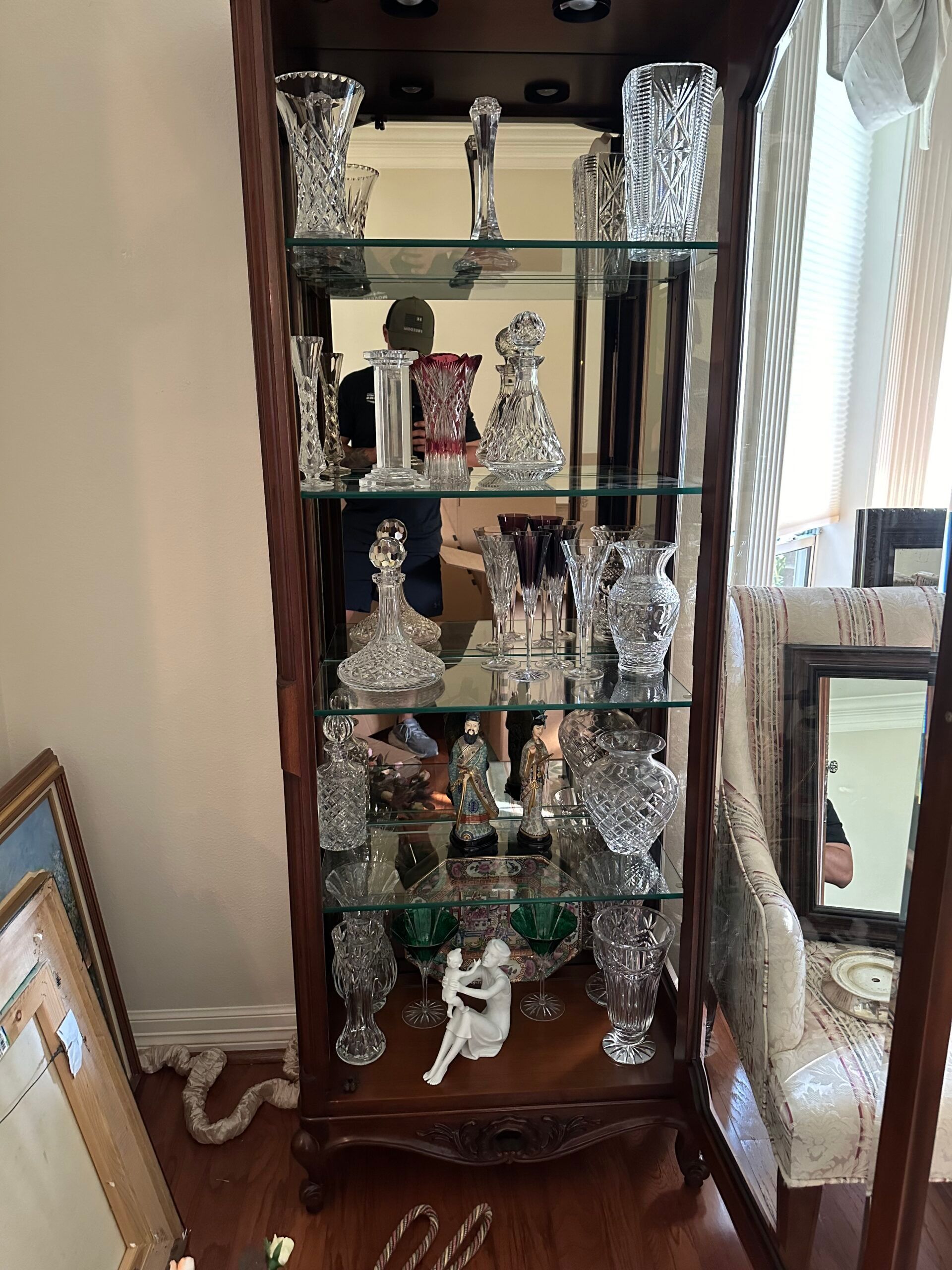 A glass display case filled with lots of delicate objects in a living room.