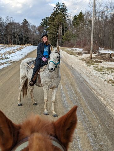 A woman is riding a horse down a dirt road.