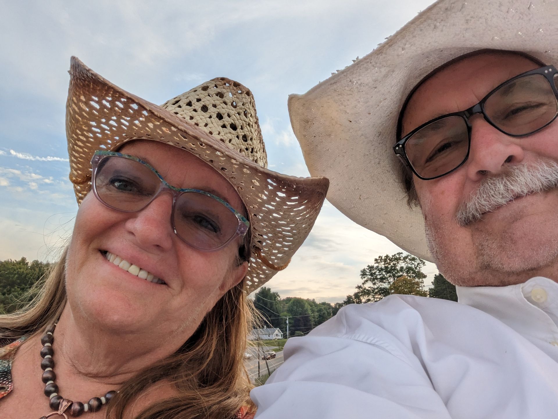 A man and a woman wearing cowboy hats and glasses are smiling for the camera.
