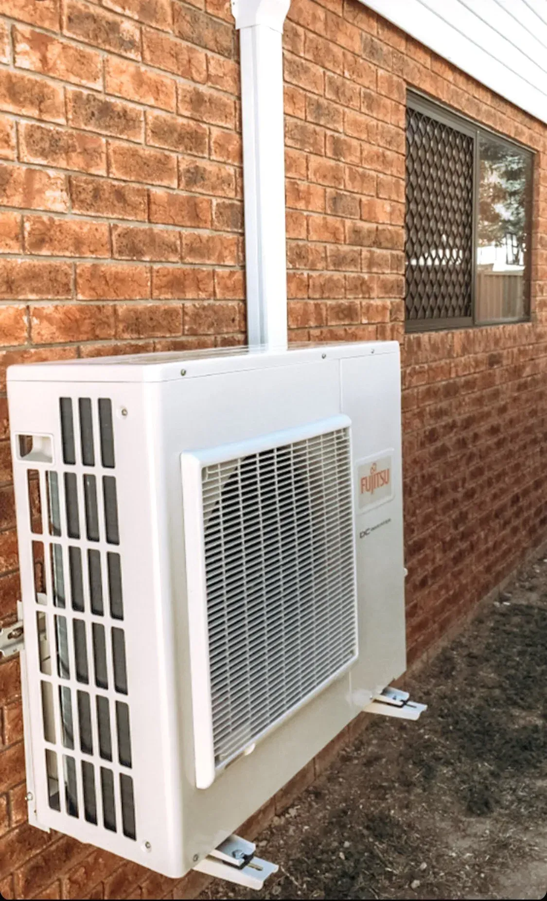 White Fujitsu Air Conditioner Mounted on a Red Brick Wall — Hazlec Services Pty Ltd in Rockyview, QLD