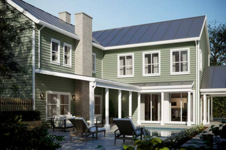 Modern two-story green house with a patio, white trim, and a solar-panel roof in daylight