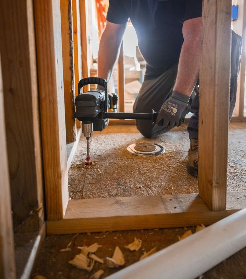 A man is kneeling down with a drill in his hand